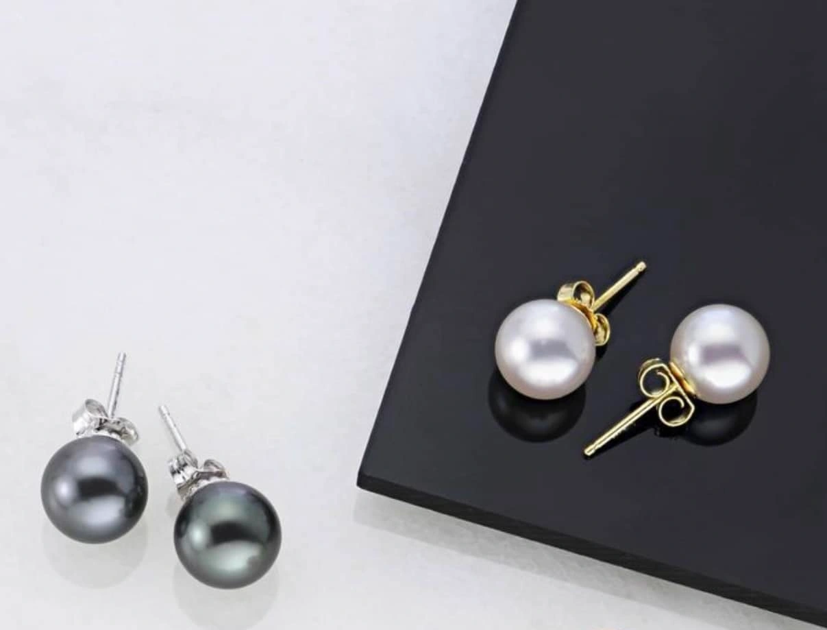 Two pairs of pearl earrings: black on the left and white on the right.