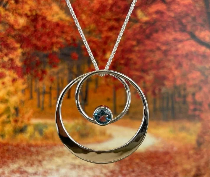 A silver necklace featuring a central blue stone.