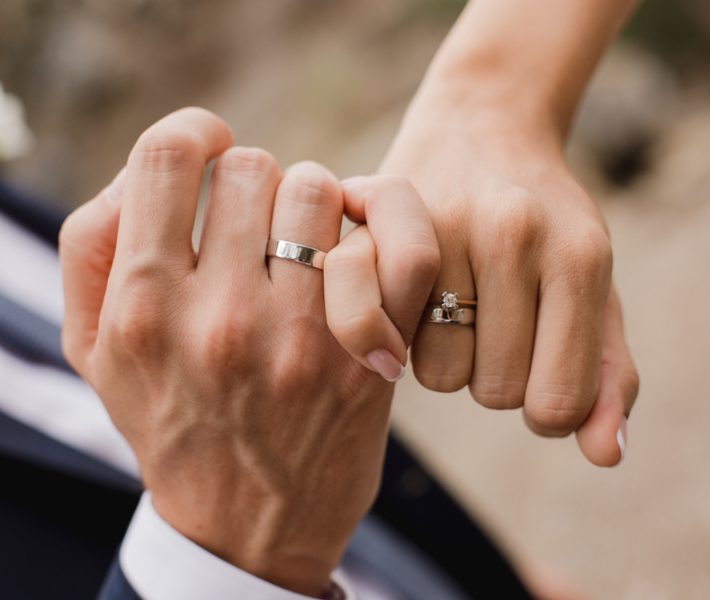 Newlywed couple's hands with wedding rings.