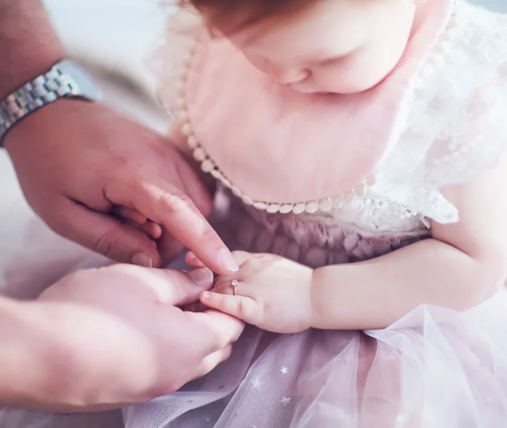 Father puts on cute golden finger ring on daughter's little hand