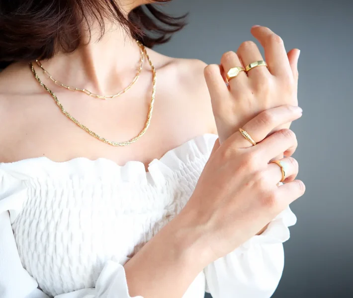 White Oval Engagement Ring with Diamond Woman’s hands close up wearing rings and necklace modern accessories elegant life style with copy space for text and background.