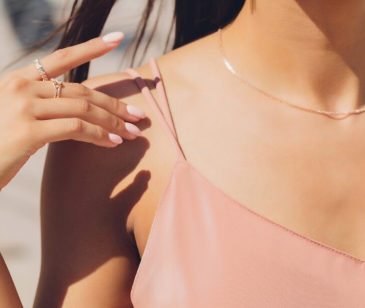 A young woman wearing a fine necklace and rings.